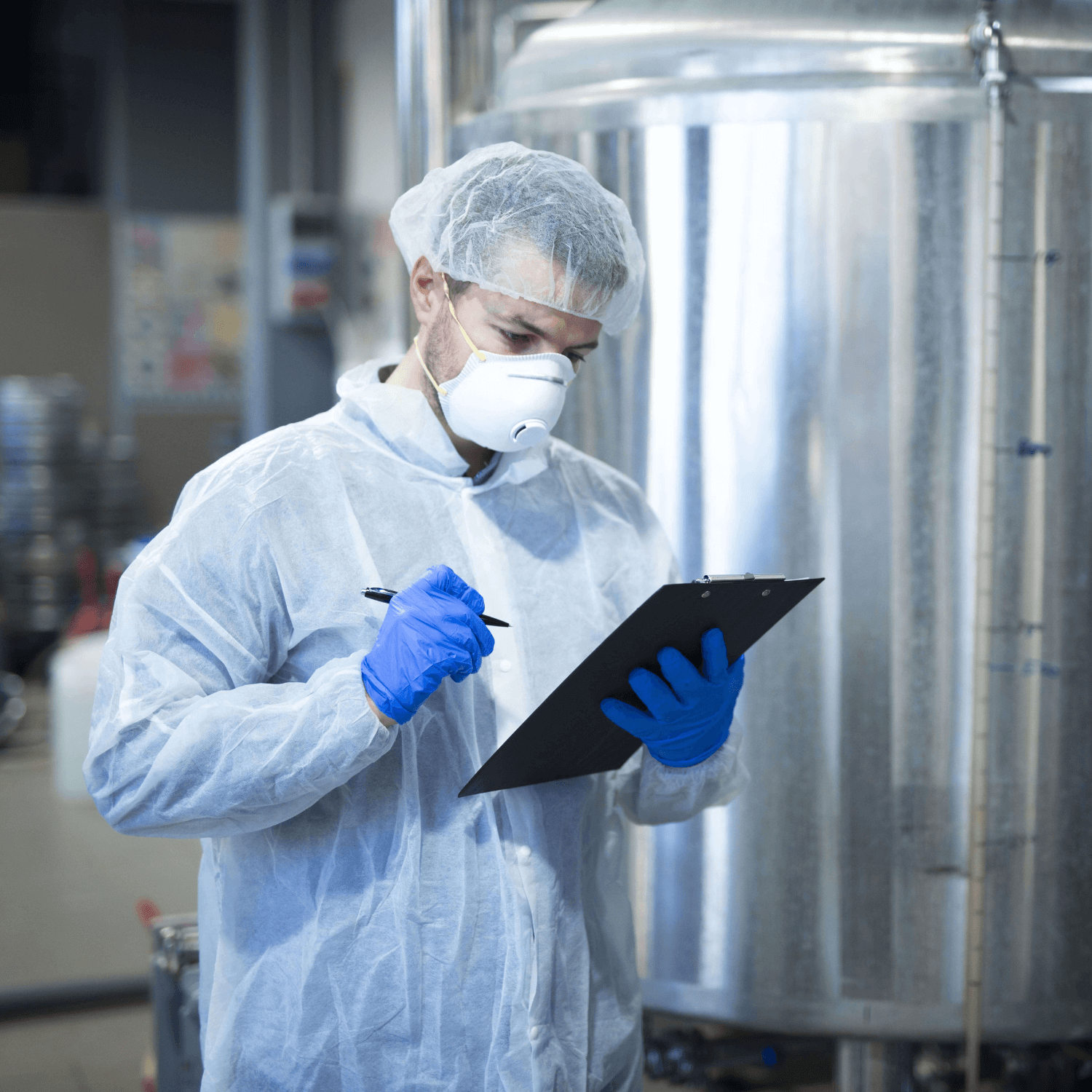 Técnico em química analisando uma prancheta ao lado de um tonel químico